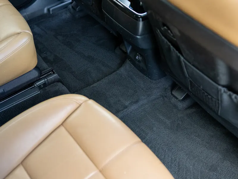 Second-row carpet after cleaning beside a tan leather captain's chair